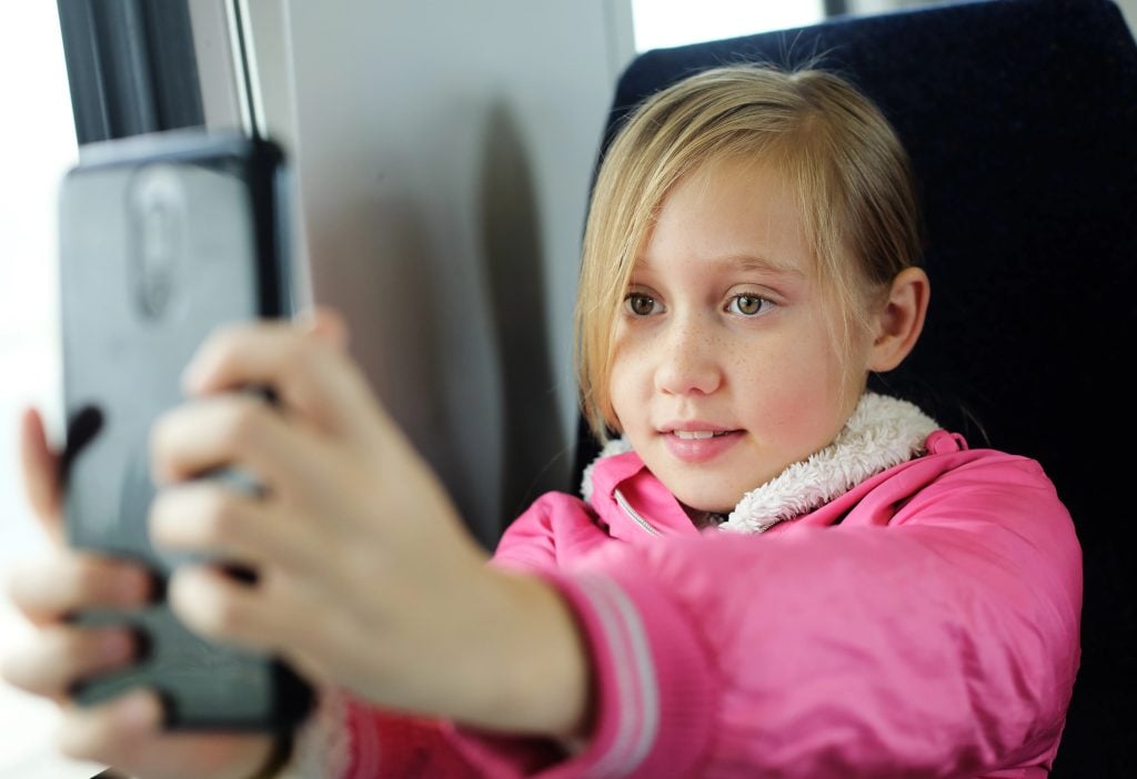 Portrait of a cheerful 9 years old girl taking a selfie