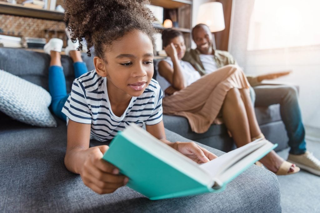 Little girl lying on couch with book