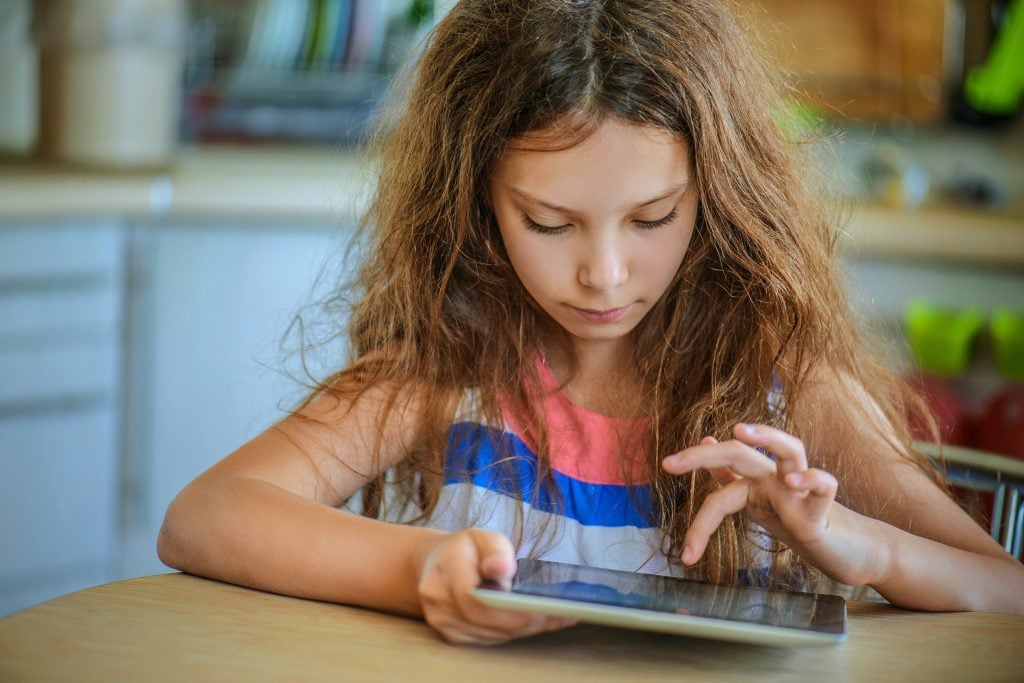 Little girl working on her homework on a tablet