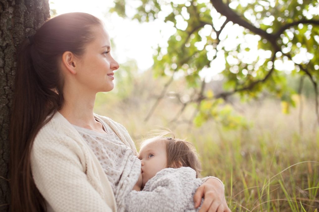 A crunchy Mother and toddler girl have rest outdoors