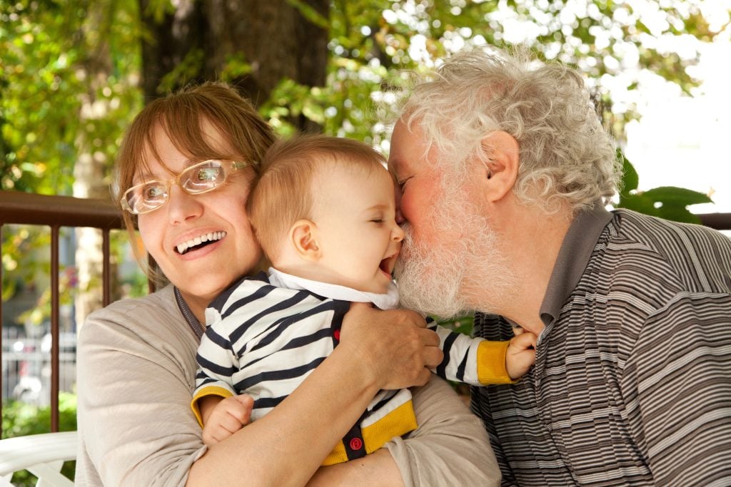 Grandparents hugging and celebrating their grandbaby
