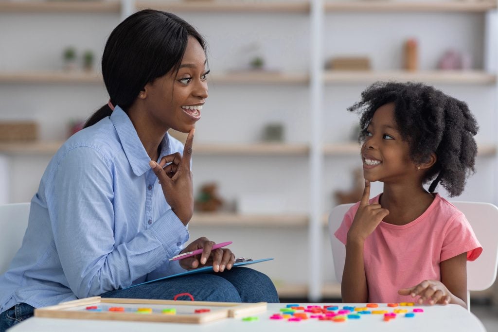 African american speech therapist working with little girl at clinic