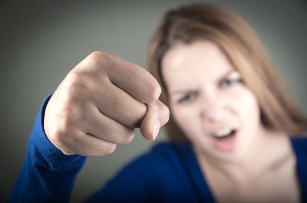 closeup portrait of angry young teen girl showing fist