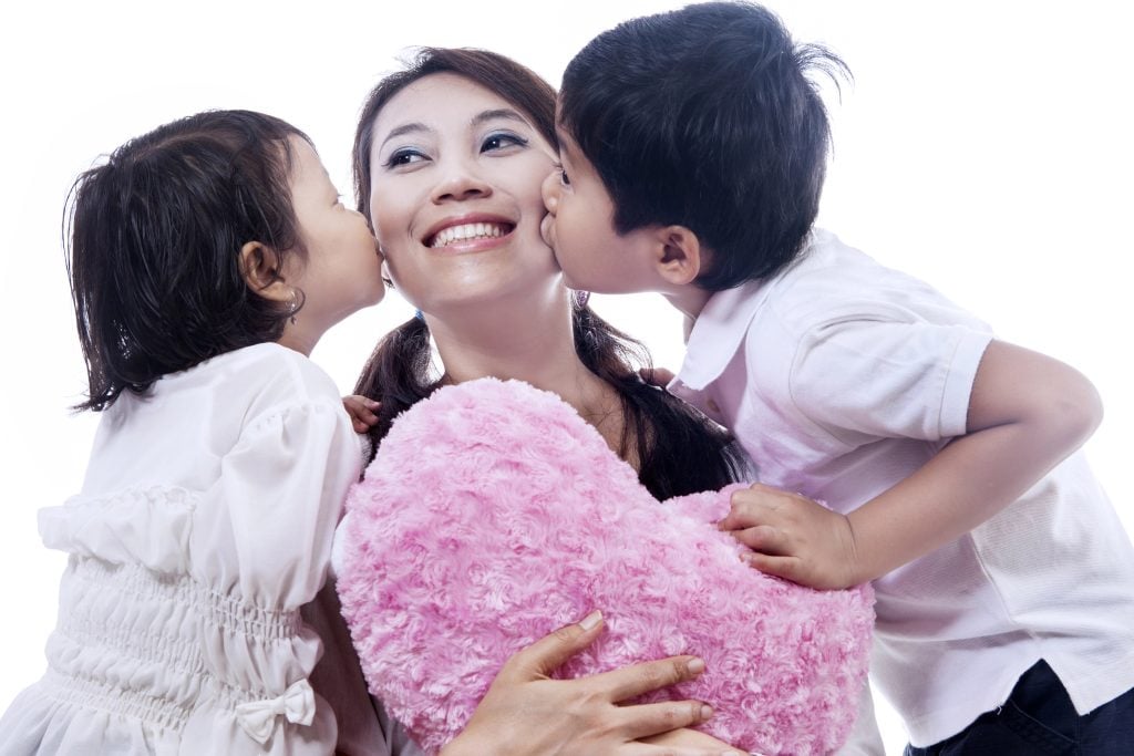 Happy mother kissed by children - isolated