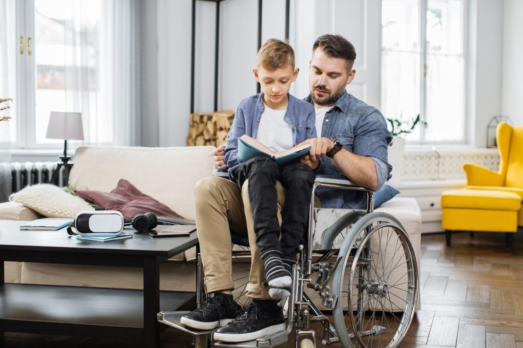 Young man in a wheelchair reading to his son for homeschool