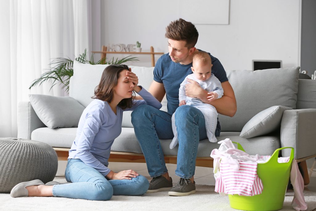 Stressed couple suffering from postnatal depression at home