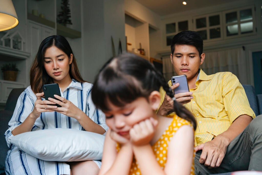 Asian little girl being ignore by her parents at home. Social addict problem.