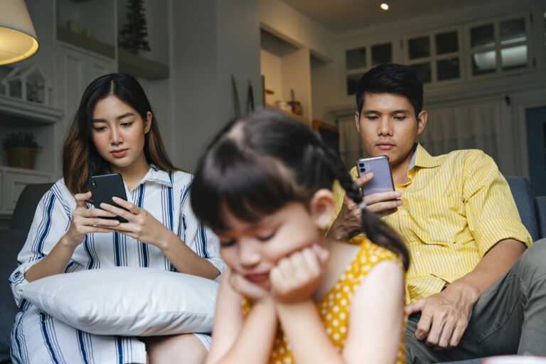 Asian little girl being ignore by her parents at home. Social addict problem.