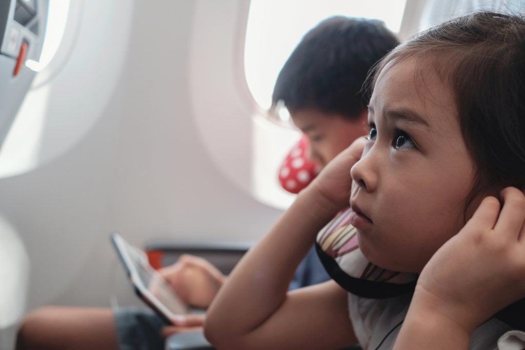 Kids using tablet and watching movies in day flight, famil