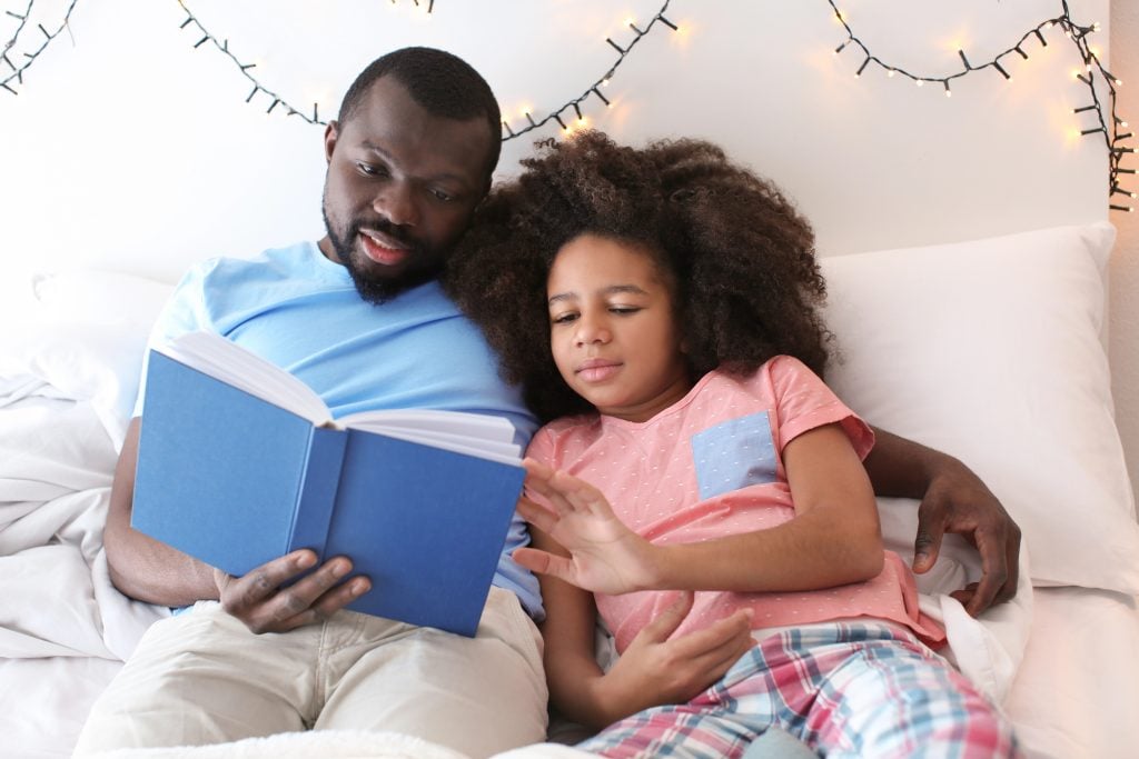 man reading bedtime story to daughter
