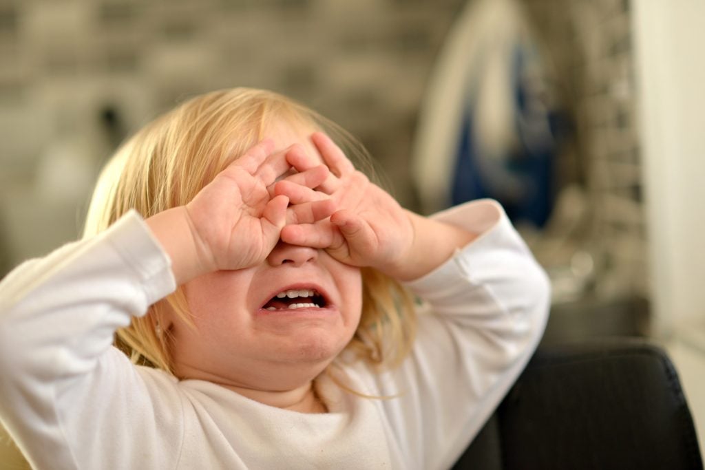 Crying toddler over their parent telling them to stop crying.