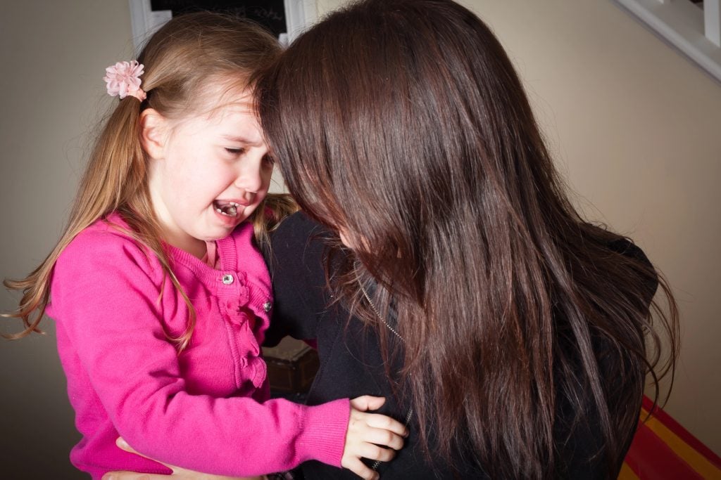 crying little girl being comforted by her mother