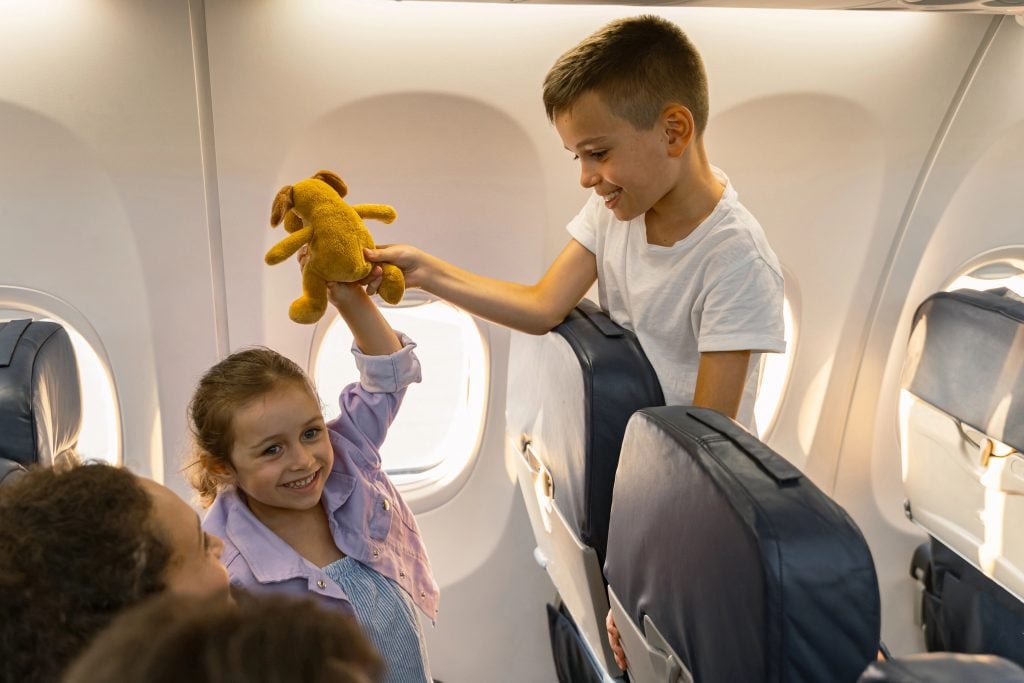 Cute kids playing on board the plane near the window