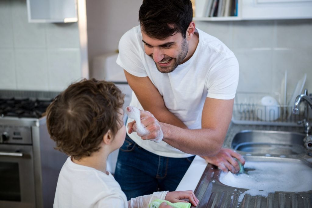 Son helping father in washing utensils