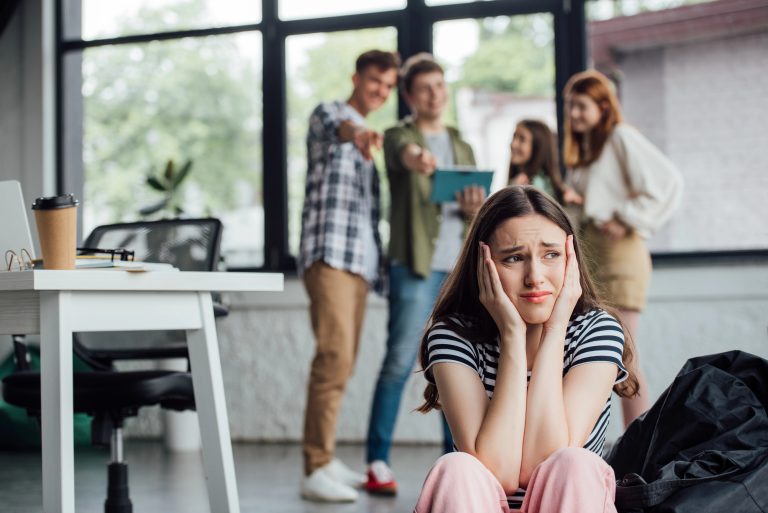 full length view of group of teenagers bullying sad girl