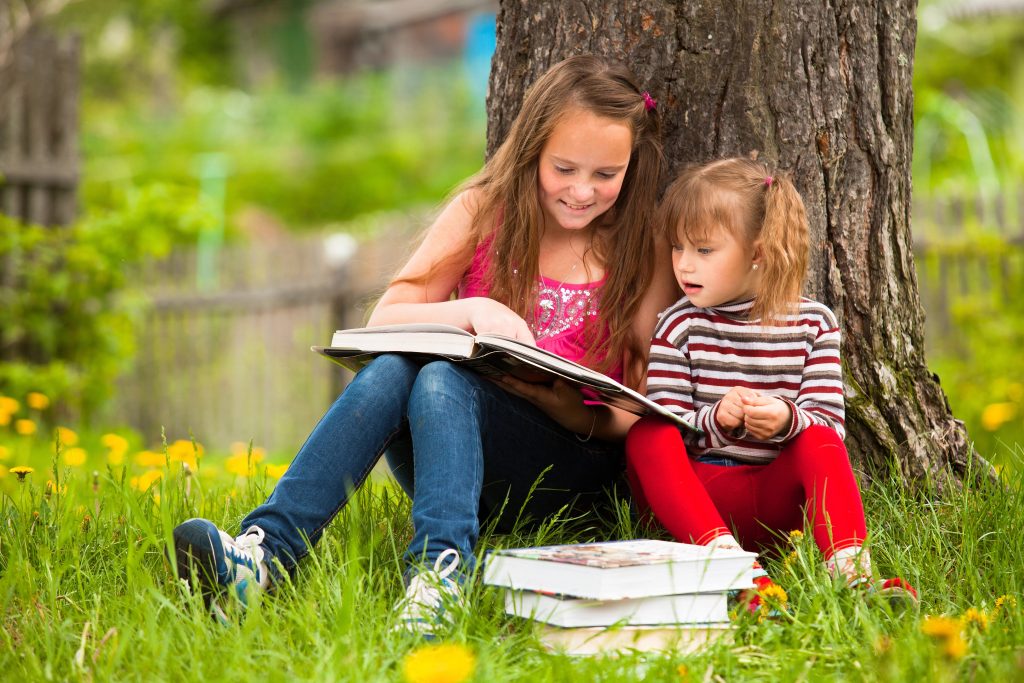 Children reading the book in summer park
