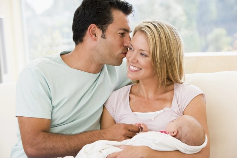 Couple in living room with baby smiling