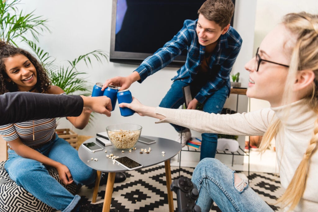 group of multicultural teens clinking with cans