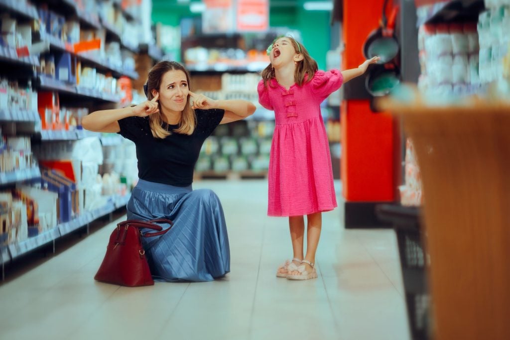 Mom Covers Her Ears When Her Child Screams in the Supermarket