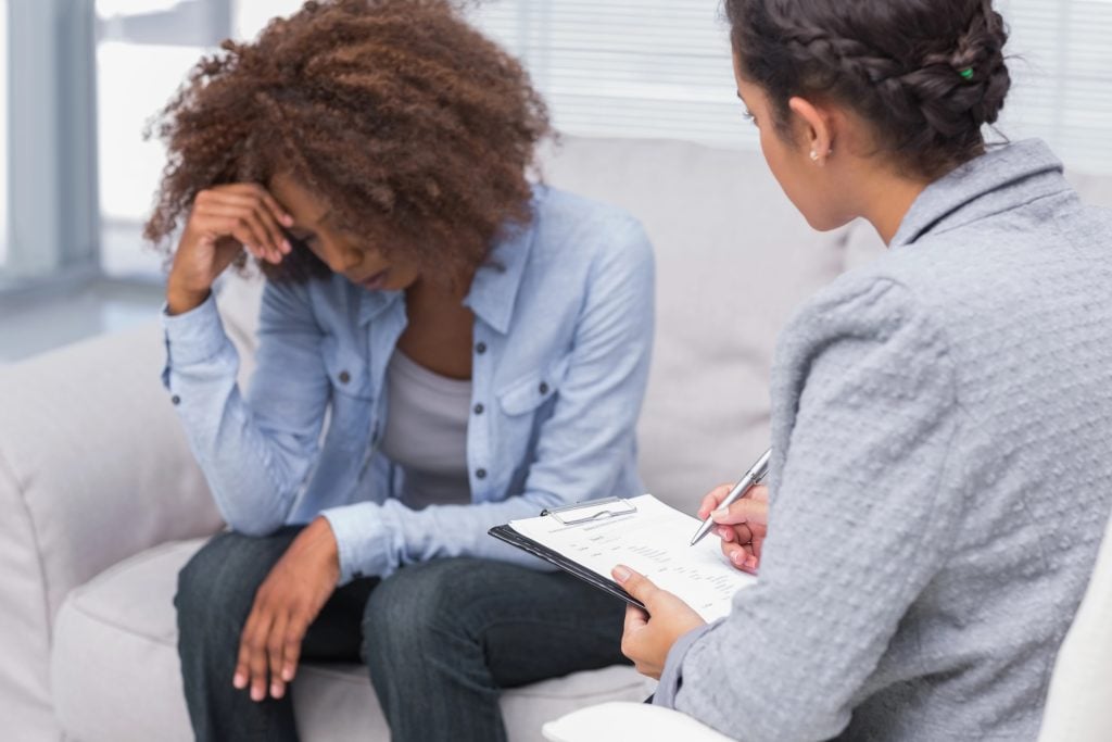 Woman sitting on therapists couch looking down