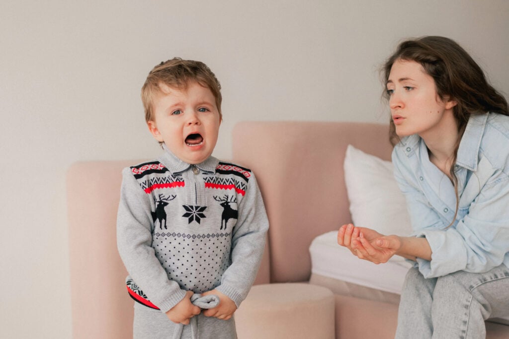 A little boy is hysterical in a three-year-old crisis, he is unhappy with a Christmas present. A mother comforts her stressed child. Concept for bullying, depression stress or frustration.