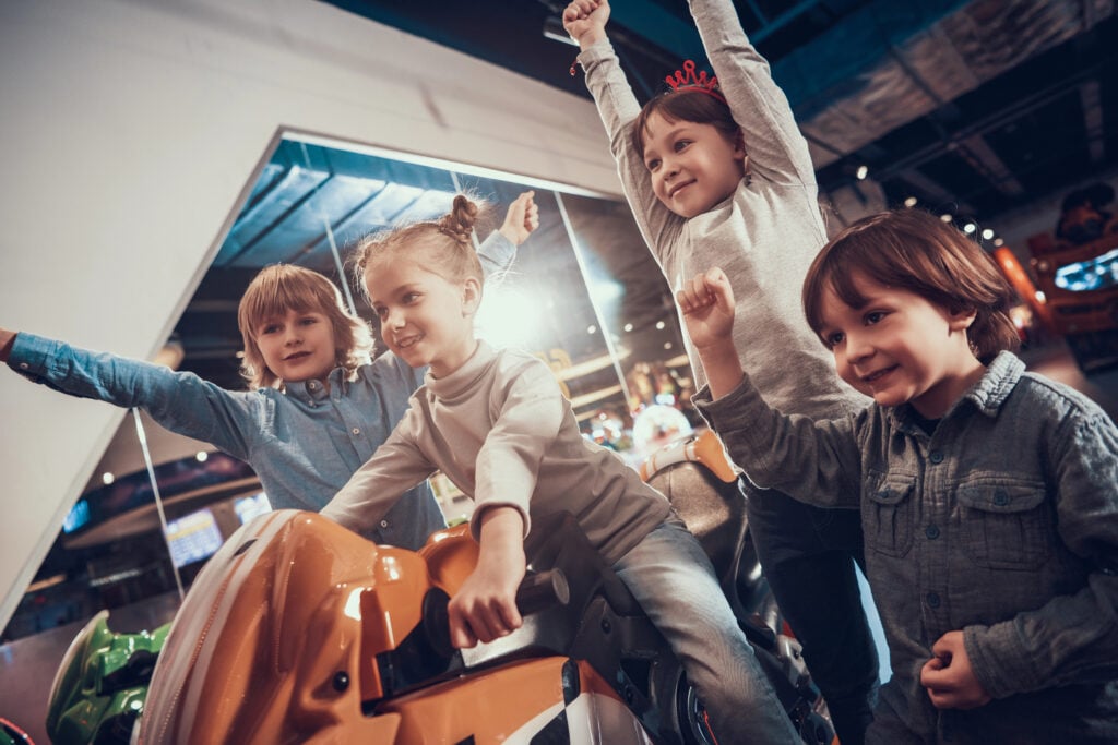 Cheerful kids playing video games on slot machine.