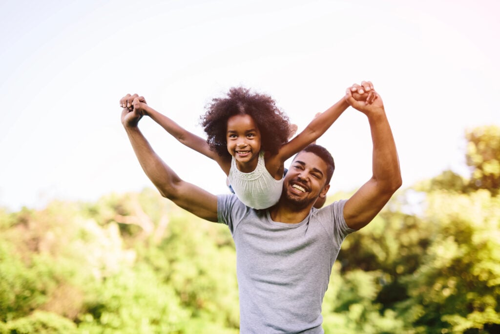 Child flying on father's shoulders