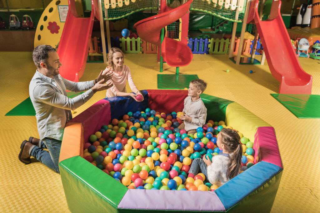 high angle view of happy family with two adorable kids playing with colorful balls in entertainment center