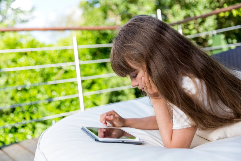 Girl playing with tablet on patio