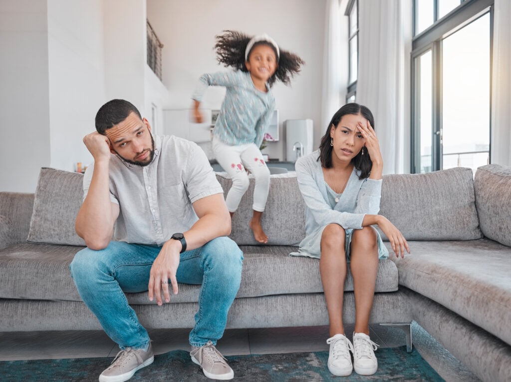 Tired, couple and family with adhd girl jump fast on sofa in house living room or home. Man, woman and parents with burnout, depression or anxiety from autism, energy and mental health kid and stress.