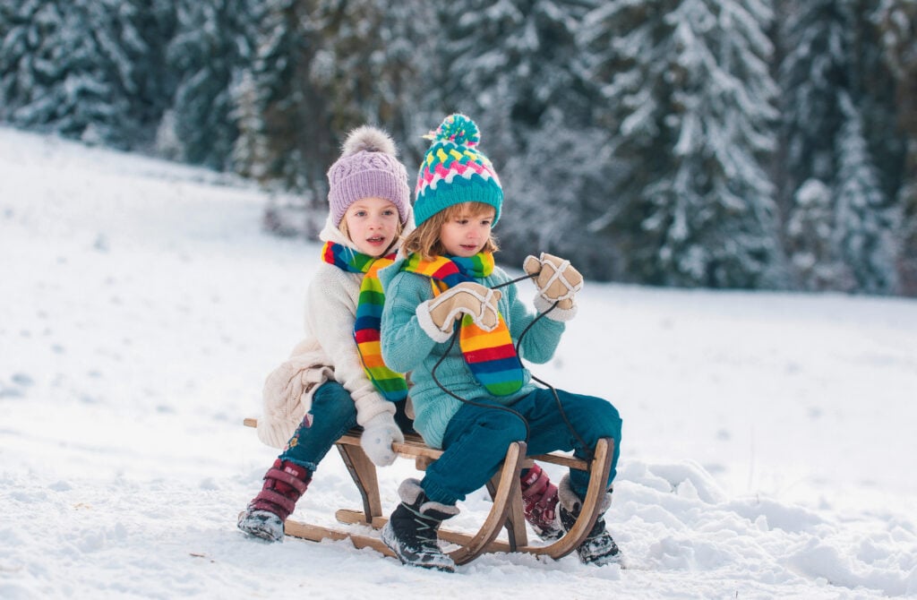 Children on sleigh. Kids boy and girl plays outside in the snow. Winter, holiday and Christmas time. New Year wallpaper, Christmas greeting card