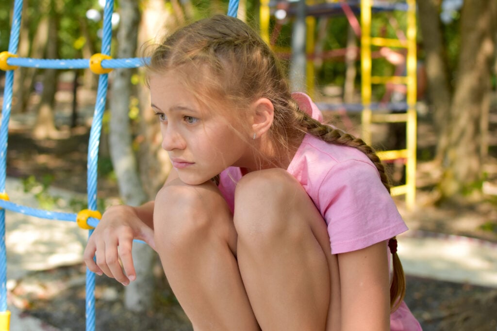 sad girl at playground. dolorous child became thoughtful.