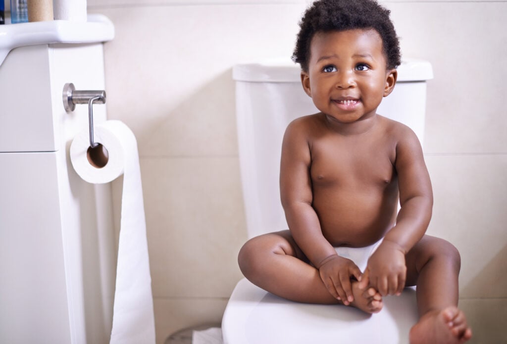 African baby boy, toilet and home with smile, learning and childhood development for potty training. Young toddler, black child or kid sitting in bathroom with diaper, growth and looking in house.