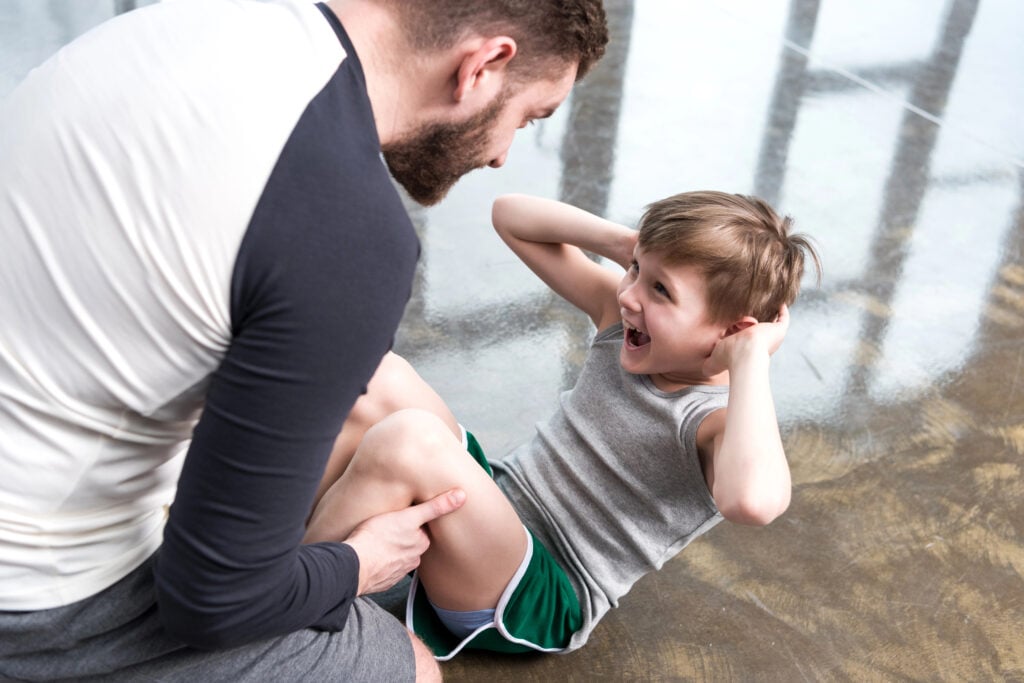 Boy doing sit-ups with his dad. 