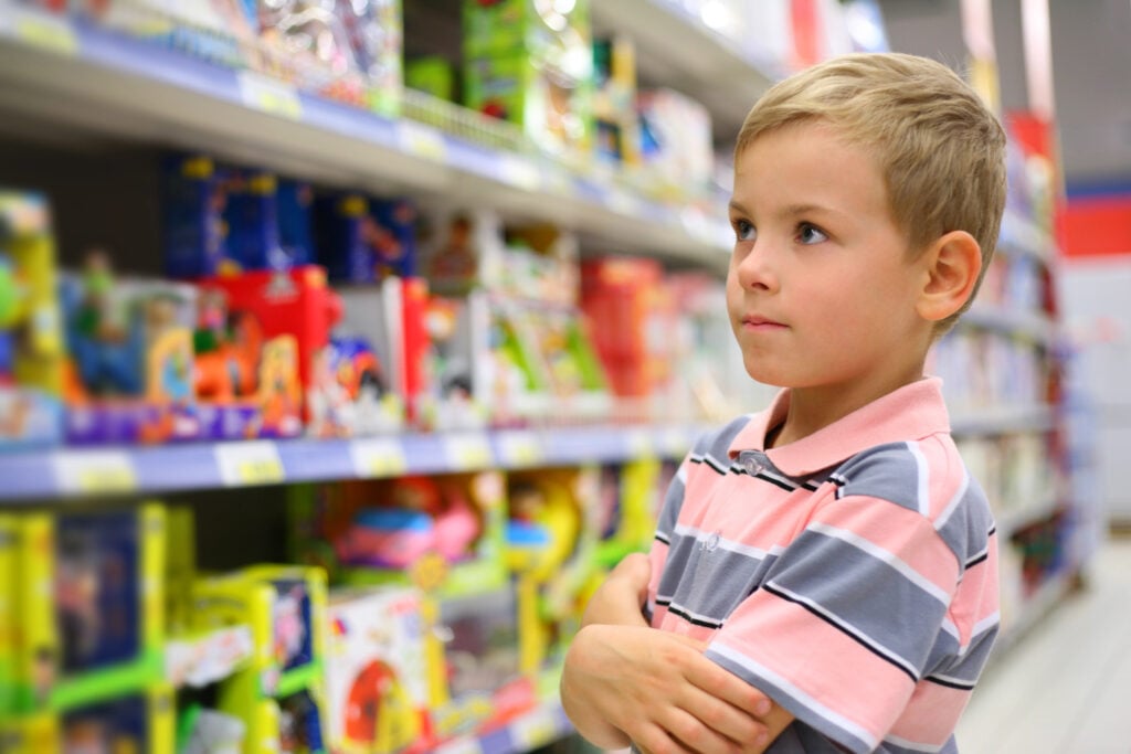 Boy looks at shelves with toys in shop
