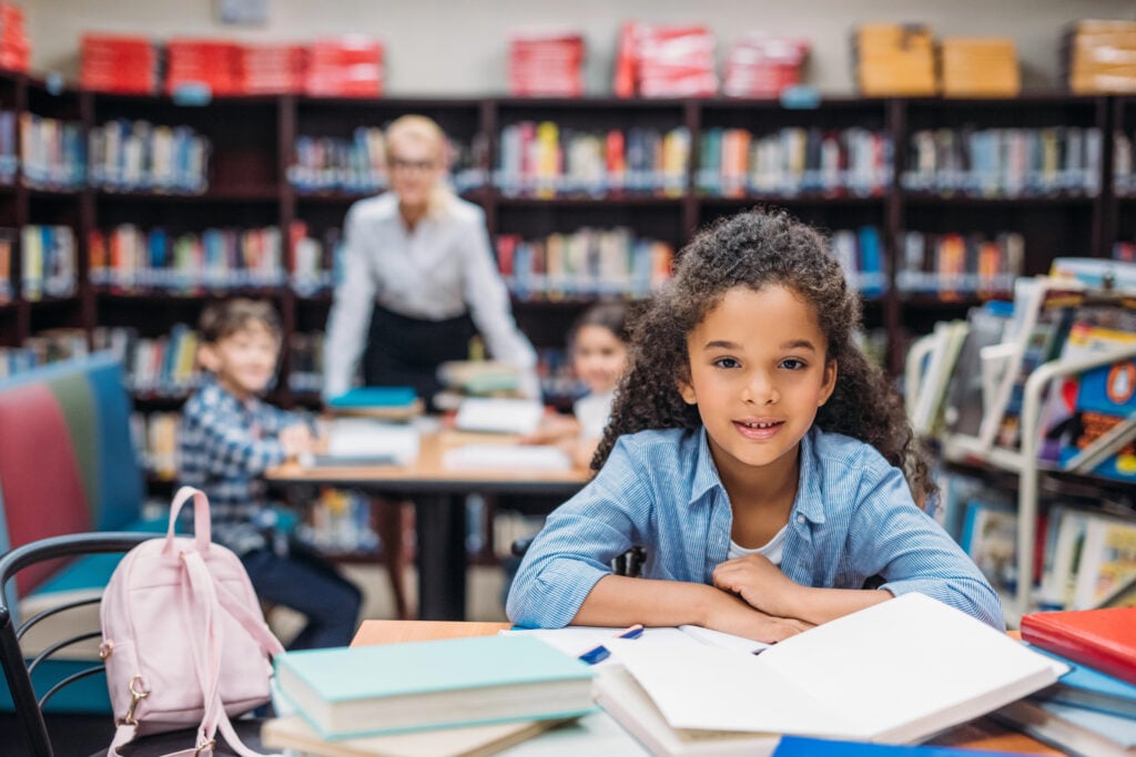 schoolgirl with pile of books at library