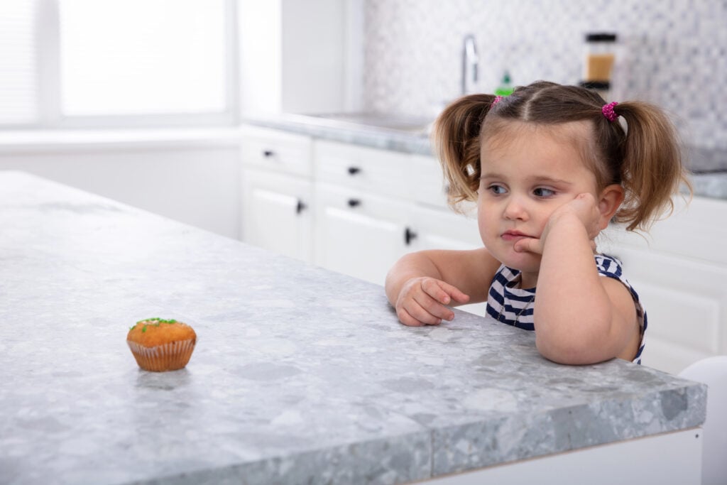 girl resisting eating a cupcake