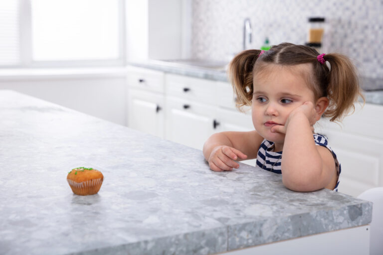 girl resisting eating a cupcake