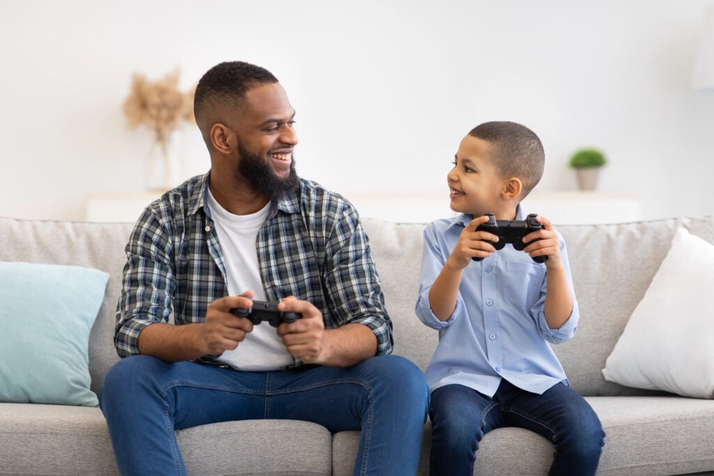 Cheerful African American Father And Son Playing Videogames At Home