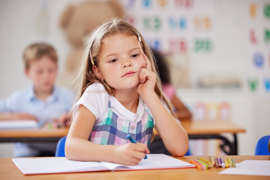 a preschool student looking thoughtful while sitting in class.