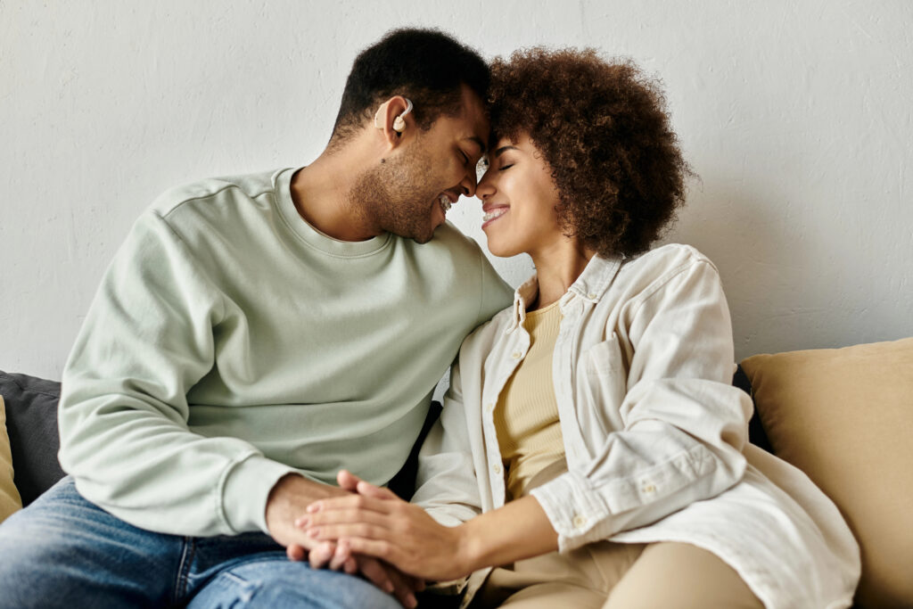 An African American couple sitting on sofa.