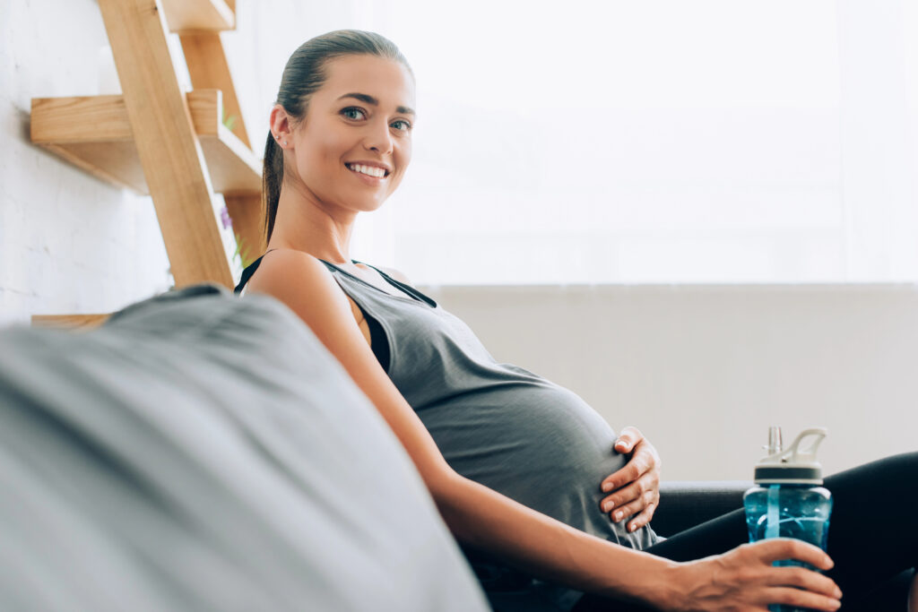 A pregnant woman with a glow, sitting on the couch.