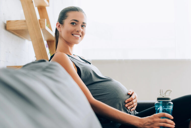 A pregnant woman with a glow, sitting on the couch.