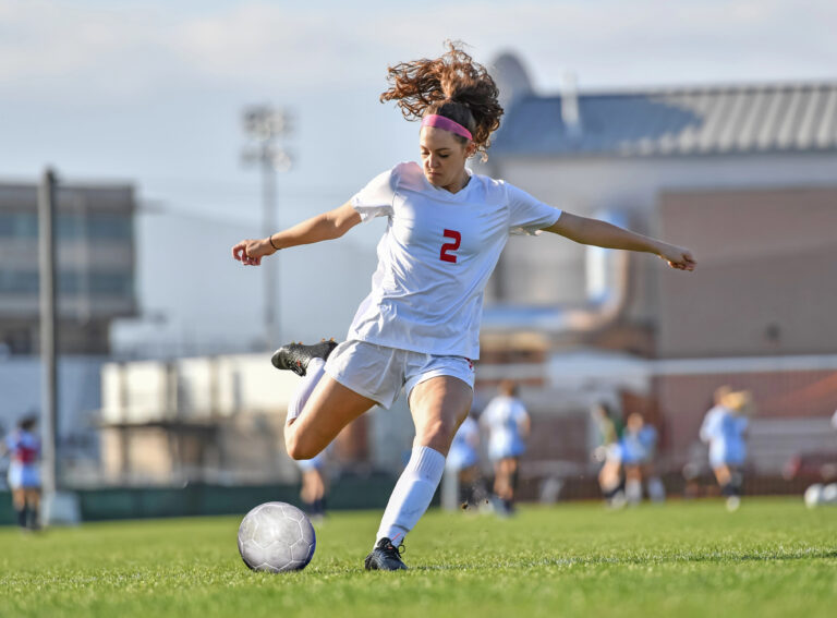 Young attractive athletic girl playing soccer in a game