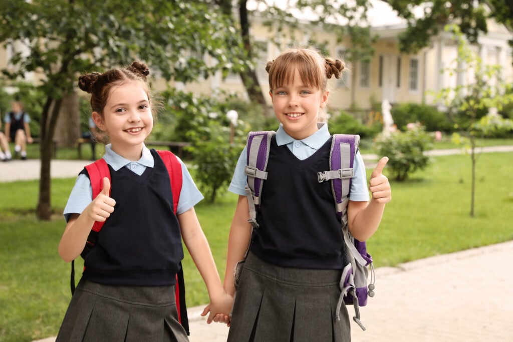 Little girls in stylish school uniform outdoors