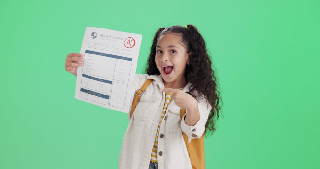 Happy student, green screen and girl with report card, pointing and excited on studio background. Portrait, mockup space and kid with education, knowledge and celebration for test results and success.