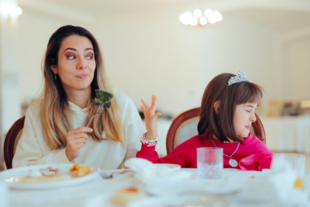 Girl Saying No to Broccoli While Mom While mom tries to convince her