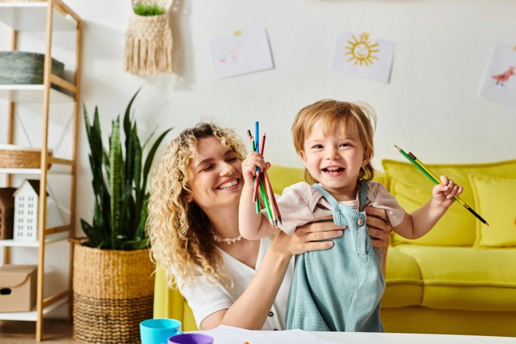A curly mother and her toddler daughter engage in Montessori learning activities at a table in a cozy home setting.