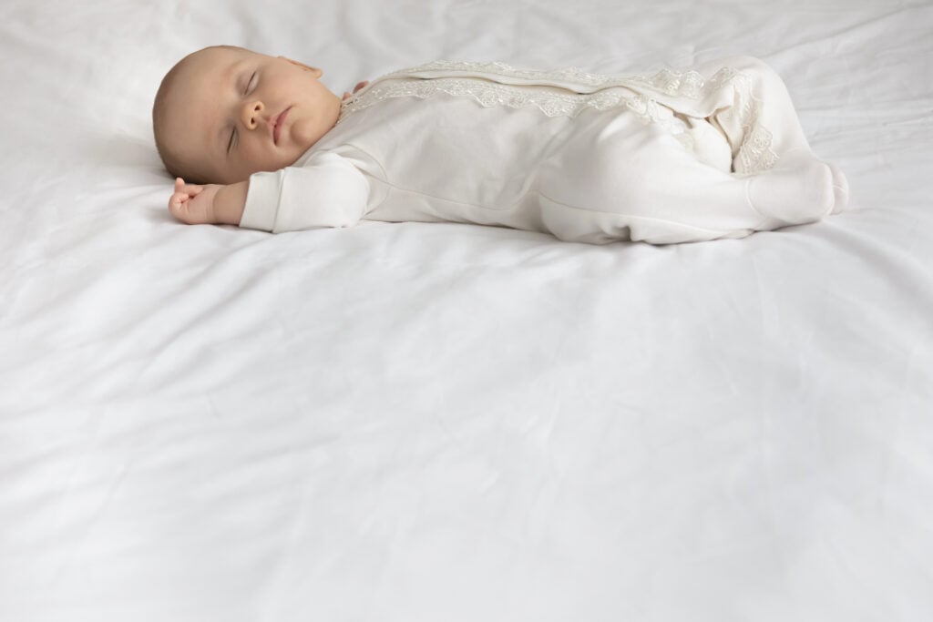 Peaceful calm sweet baby wearing body sleeping on soft mattress