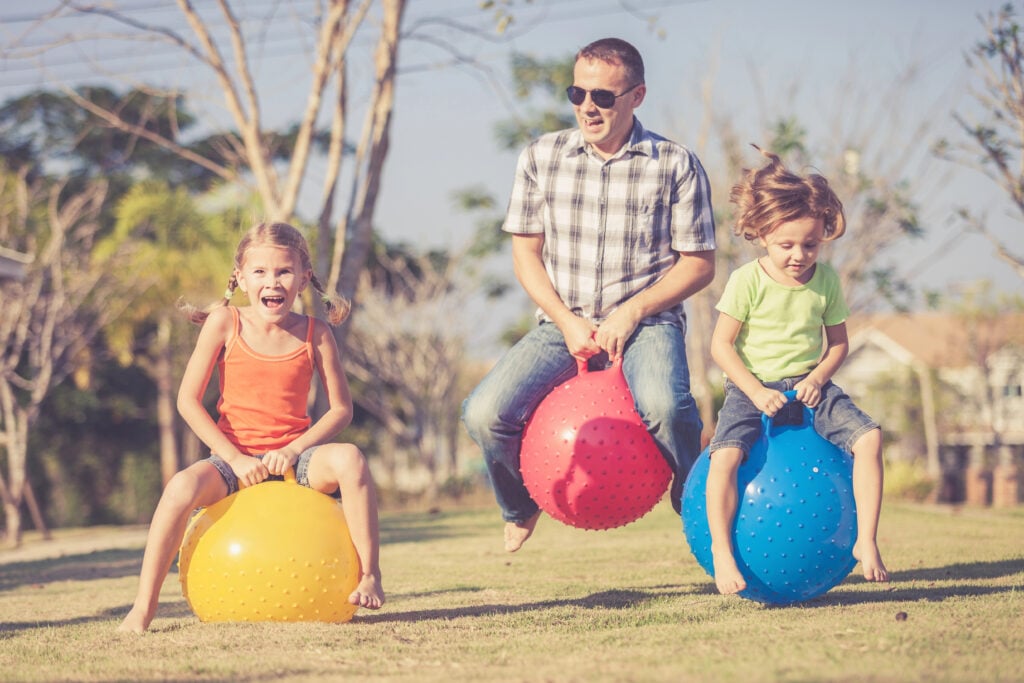 Dad and children playing on the lawn in front of house